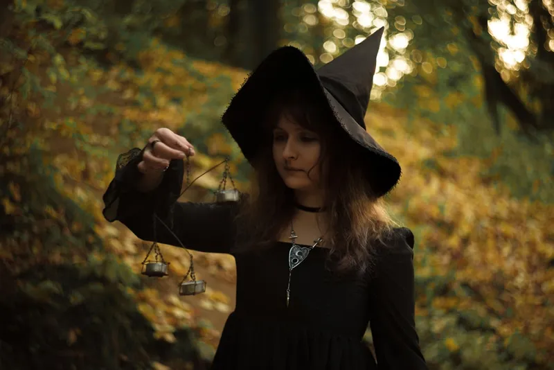 woman in black long sleeve shirt and black hat holding a stick